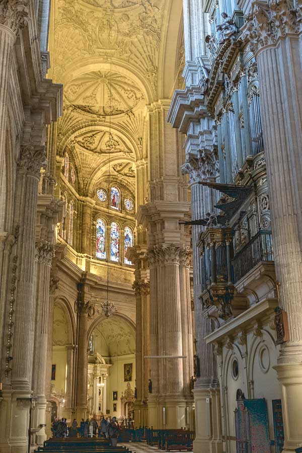 dimly lit interior of malaga cathedral with columns and soaring side aisle