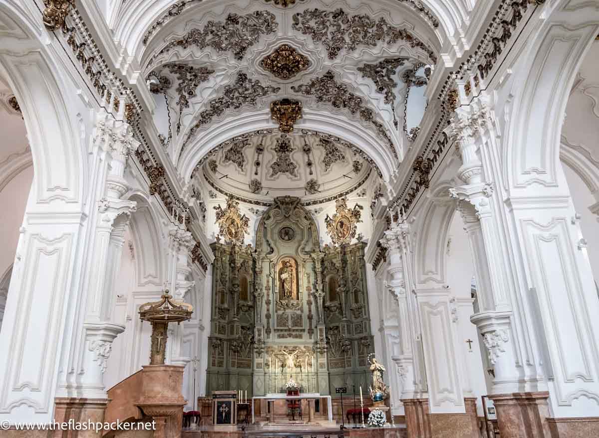 oprnate interior of baroque church with white pillars and altar