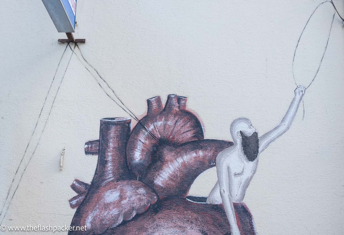 small wall mural of naked man climbing out of a heart