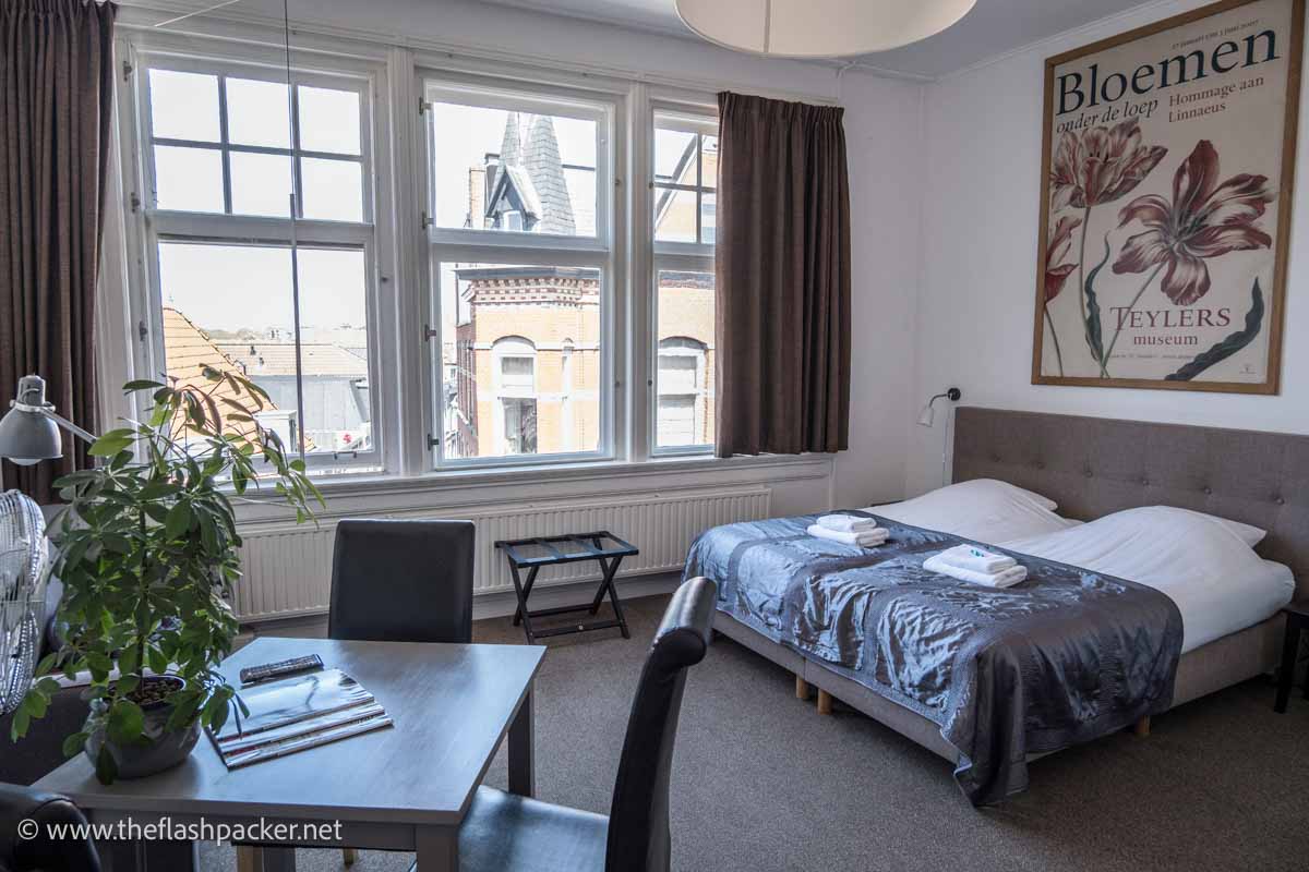 room in malts hotel haarlem with large window, table and chairs and a large bed