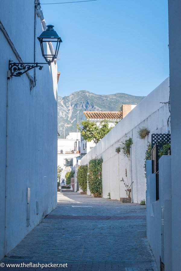 narrow lane with whitewashed buildings and mountains in background