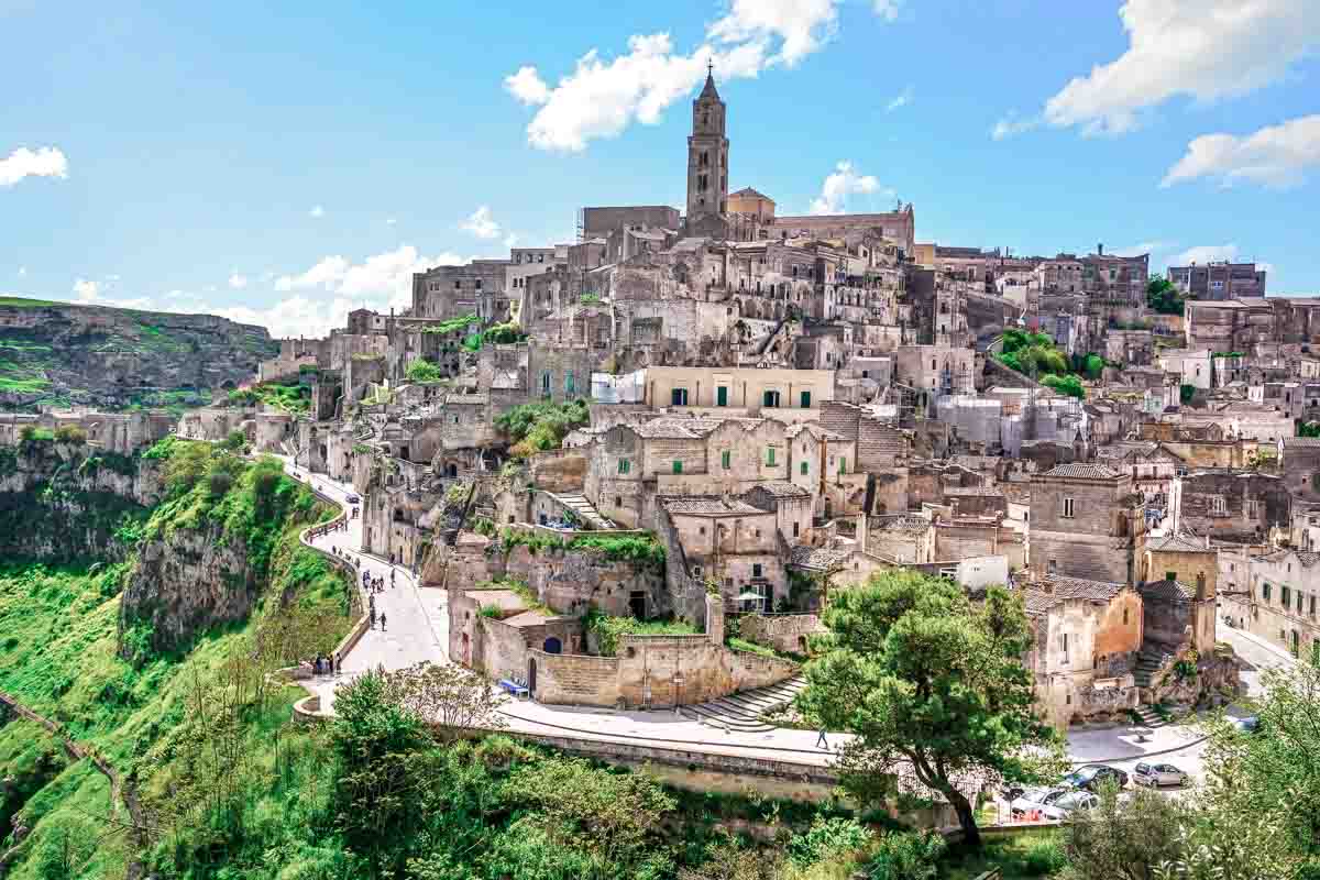 hilltop town of Matera with grey stone buildings rising up to a church bell tower 