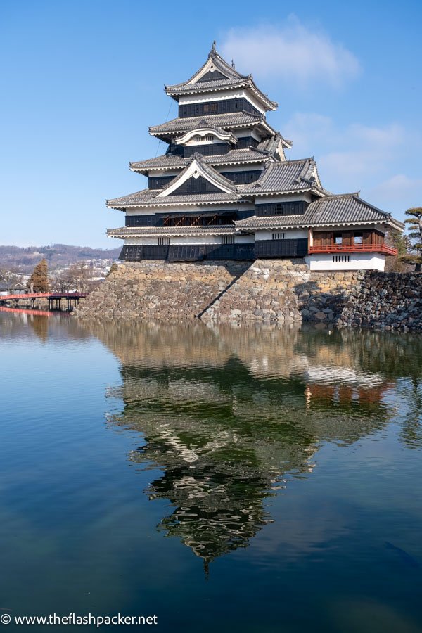 matsumoto castle reflected in the still water of moat