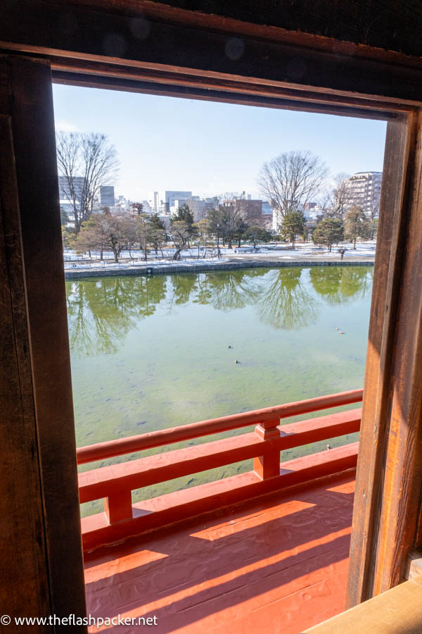 a view through a wooden window frame across a castle moat