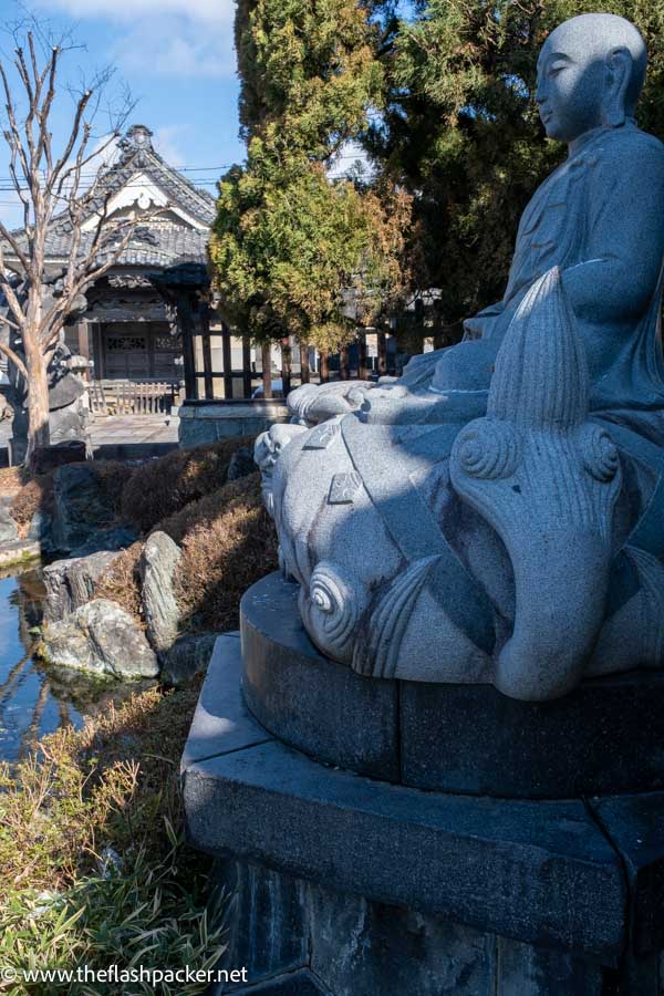 stone sculpture in front of a japanese shrine