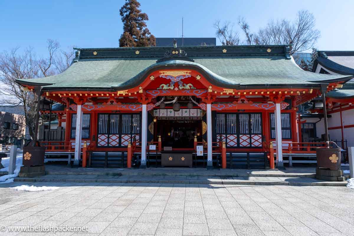 exterior of matsumoto fukashi shrine with a painted red frontage