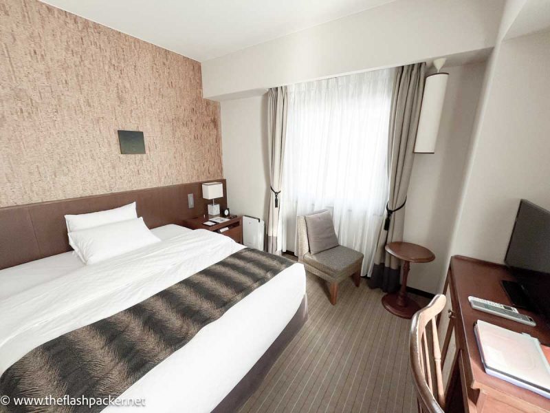 hotel bedroom with large bed and brown wooden furniture