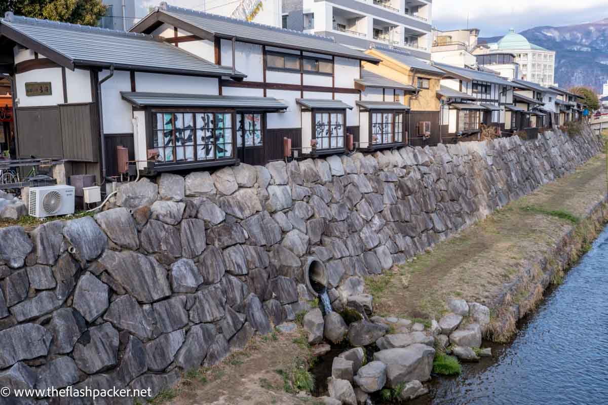 row of traditional wooden framed houses by side of river in matsumoto japan