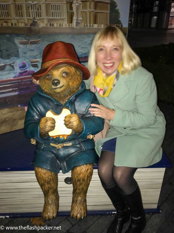 woman with her arm around a sculpture of Paddington bear