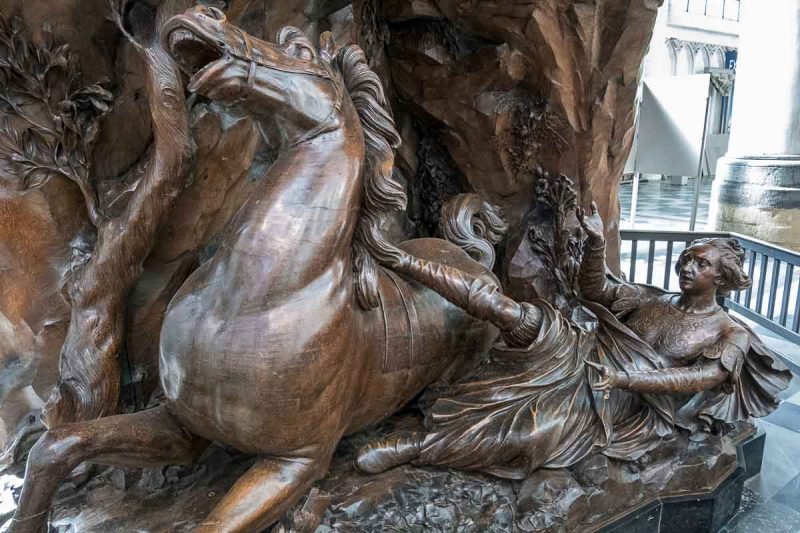 oak sculpture of man falling off horse