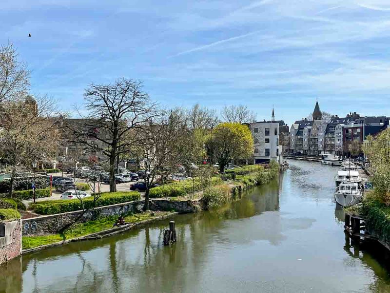 river with a few boats and lined with trees and houses