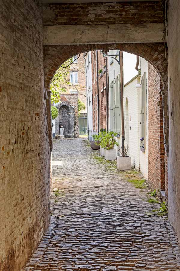 narrow cobblestone lane lined with old houses in red and painted white brick