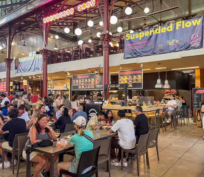 people dining at tables inside a covered market in florence