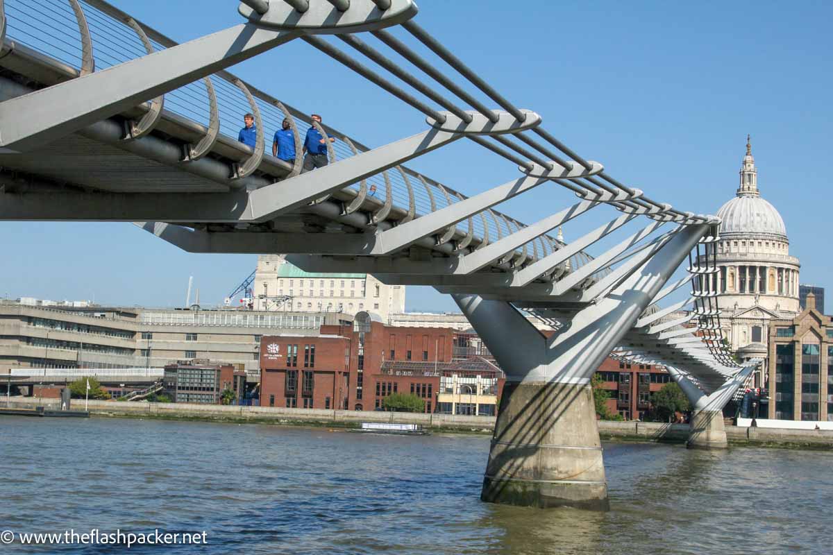 low angle view of footbridge crossing the river thames with dome of cathedral on far shore