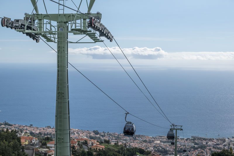 cable cars travelling between monte and funchal with the rootfops and bay below