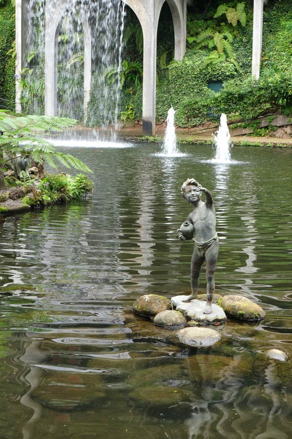 small statue of a boy holding an urn in the middle of a lake