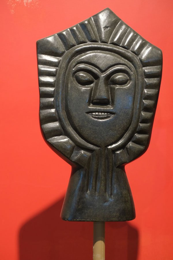 african stone sculpture of a face against a red background at monte palace museum