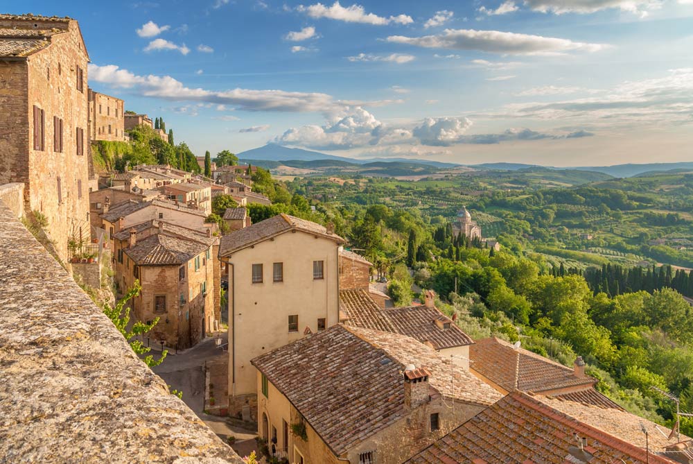 town of warm stone buildings on a hillside overlooking tuscan landscape