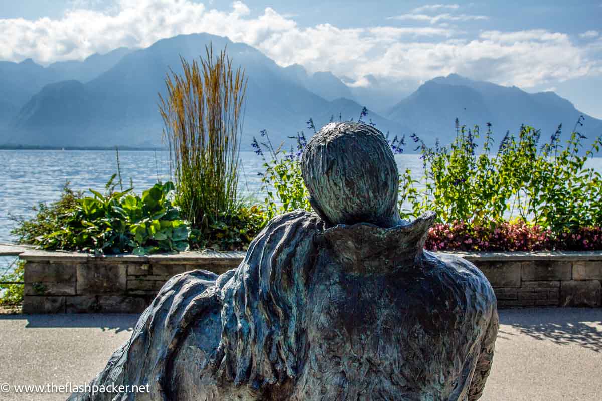 bronze sculpture of couple cuddling on bench looking out at lake montreux