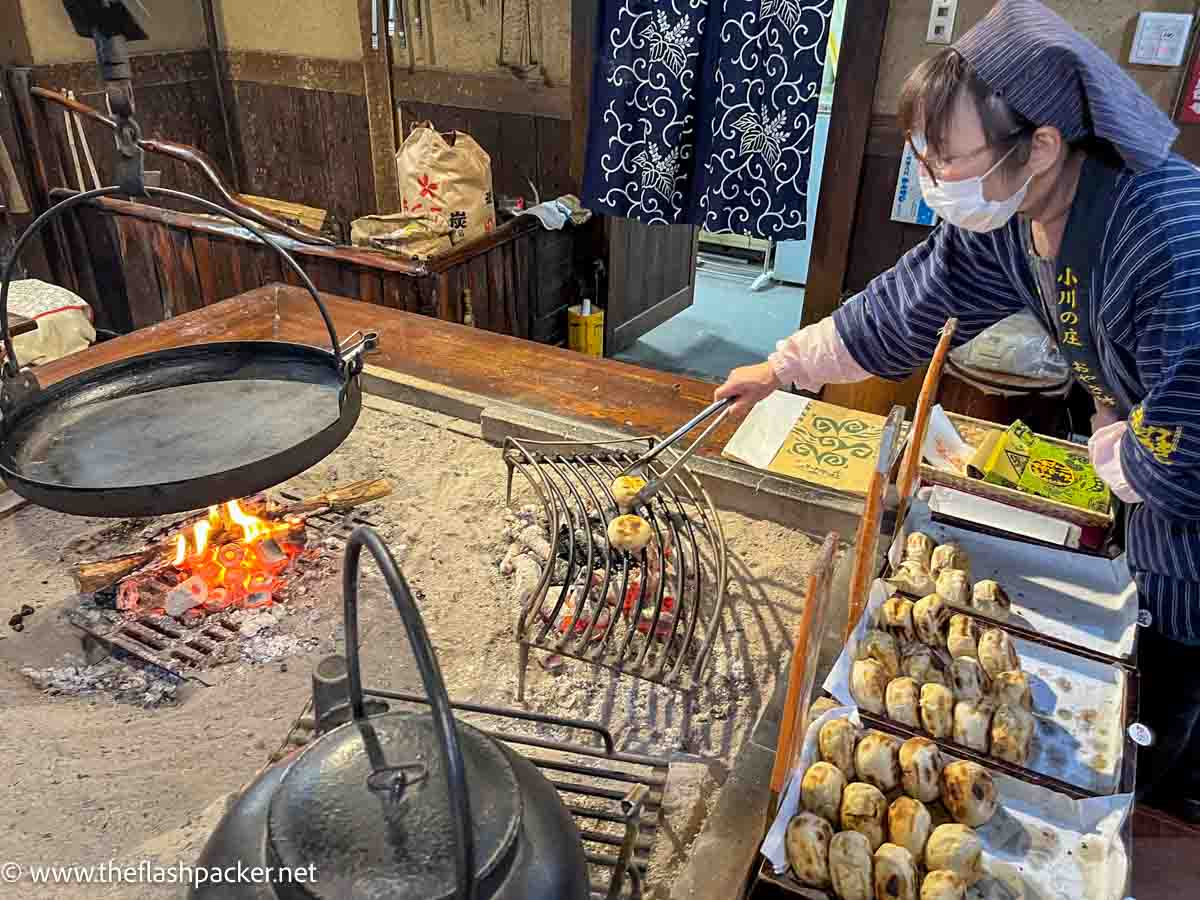 japanese woman grilling dumplings over an open flame