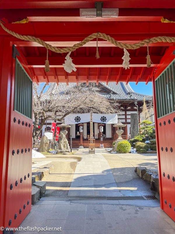 orange-red wooden gate at entrance to a small temple in nagano japan