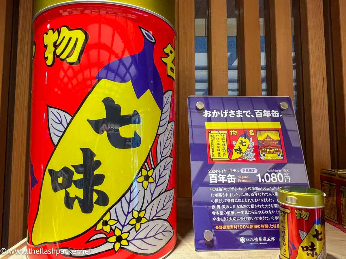 a shop display featuring a brightly colored tin of japanese spices next to a giant version of the same