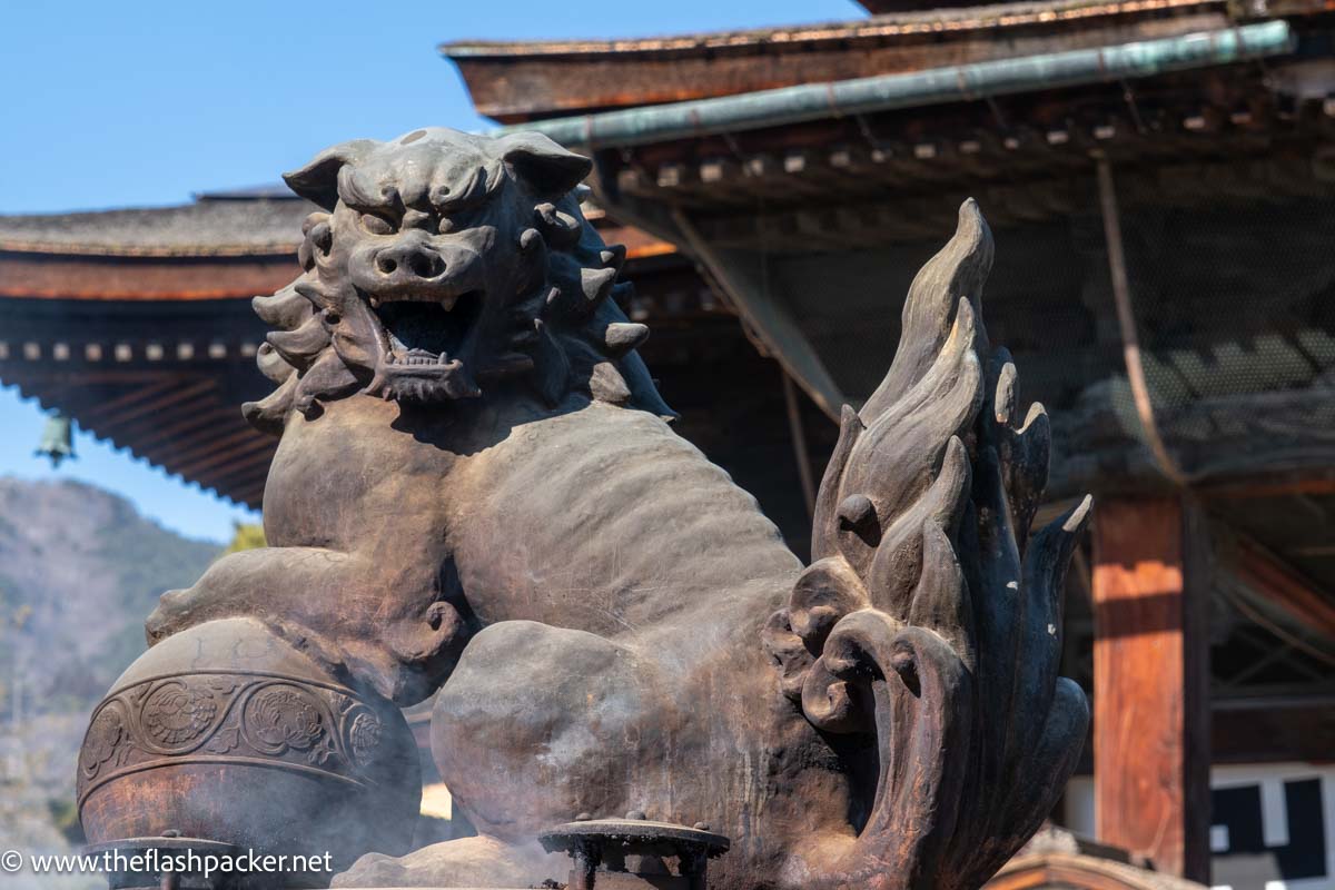 a large stone griffin type creature at the entrance to zenkoji temple in nagano japan