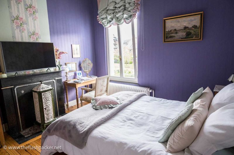 bedroom in a guesthouse with purple walls and white bed linen