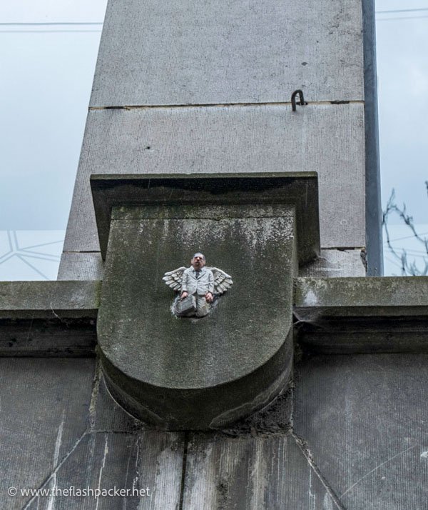 sculpture of small man on the side of a building