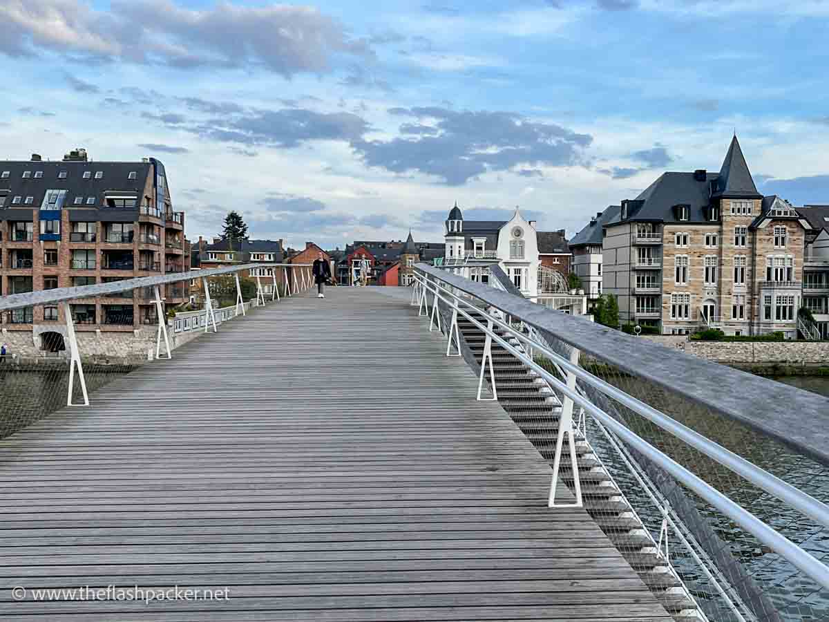 person walking across a wooden pedestrain bridge