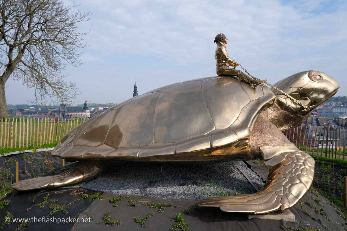 sculpture of man riding a giant turtle