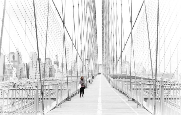 woman walking across the brooklyn bridge which is one pf the best places to travel alone in the usa