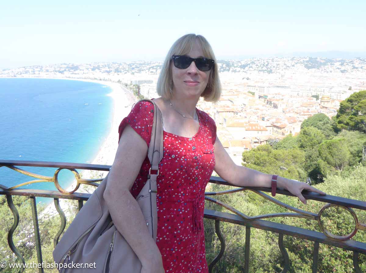 woman in a red dress on a promenade overlooking the beach in nice france