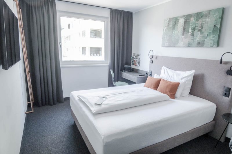 bedroom atnight inn bahnhof city feldkirch with grey palette and bed dressed in white linen