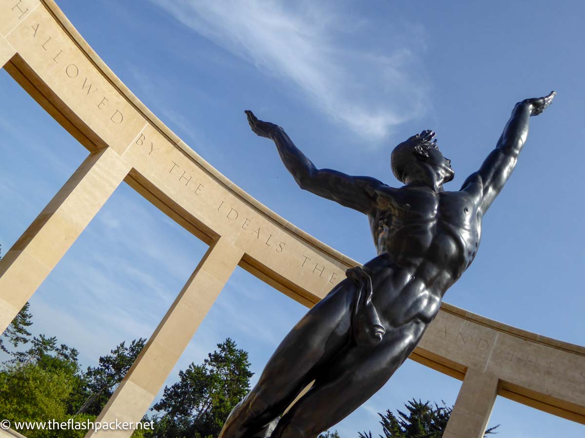 bronze sculpture of male figure with arms outstrectched