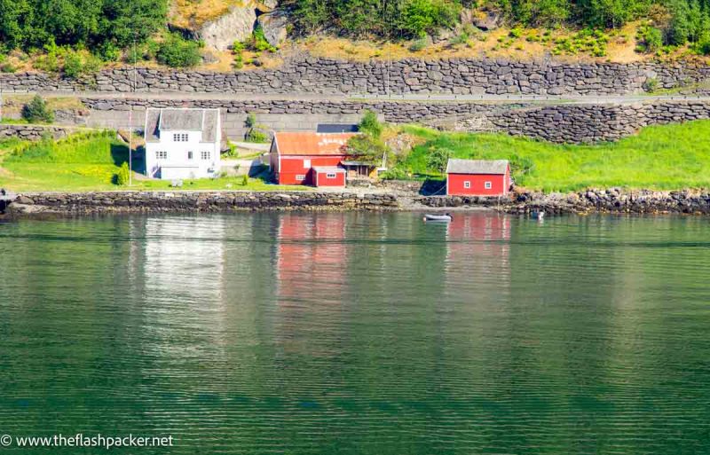 red and ochre wooden houses at side of norwegian fjord