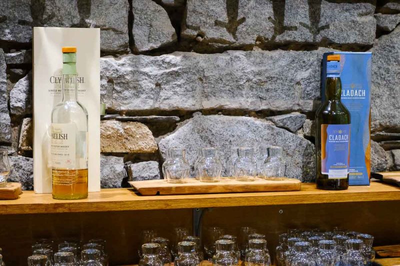 shelf against a brick wall with 2 bottles of whisky