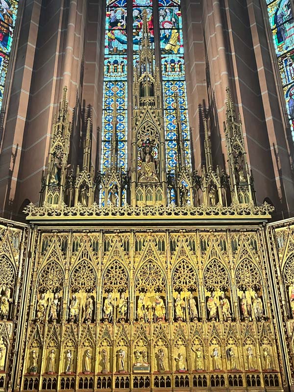 magnificent lacy golden altar with gothic stained glass window in background