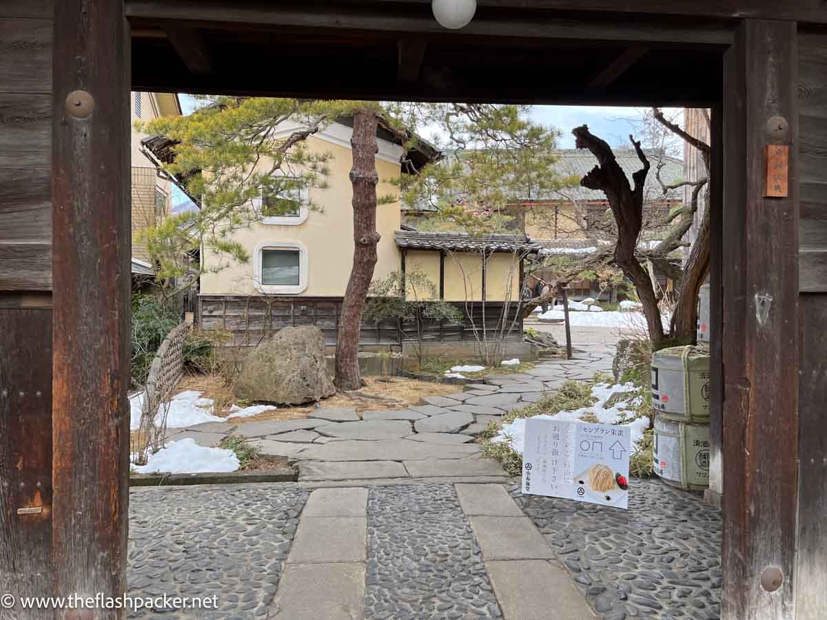 wooden gateway into courtyard with traditional japanese buildings