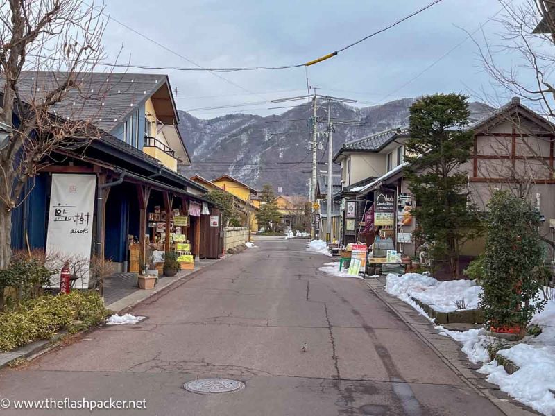 pretty street lined with traditional japanese buildings with mountains in background