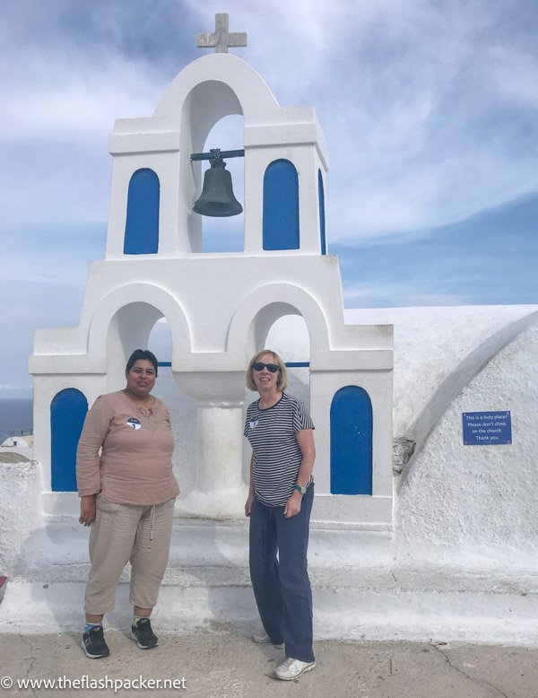 2 women standing in front of a blue and white greek church