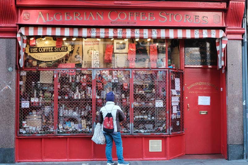 woman looking in wondow of coffee shop on old compton street which is one of londons most iconic streets