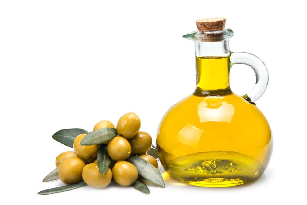 jug of olive oil with a pile of olives