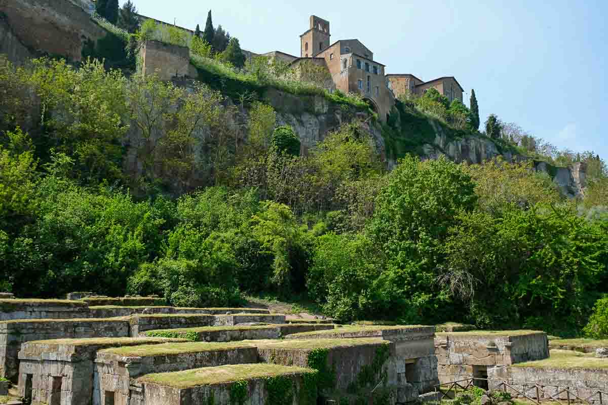 ancient necropolis with old buildings of orvieto high on cliff in background