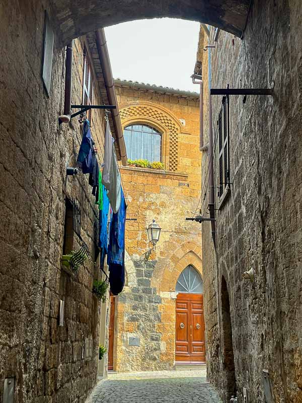 narrow alley in orvieto italy with laundry hanging outside building