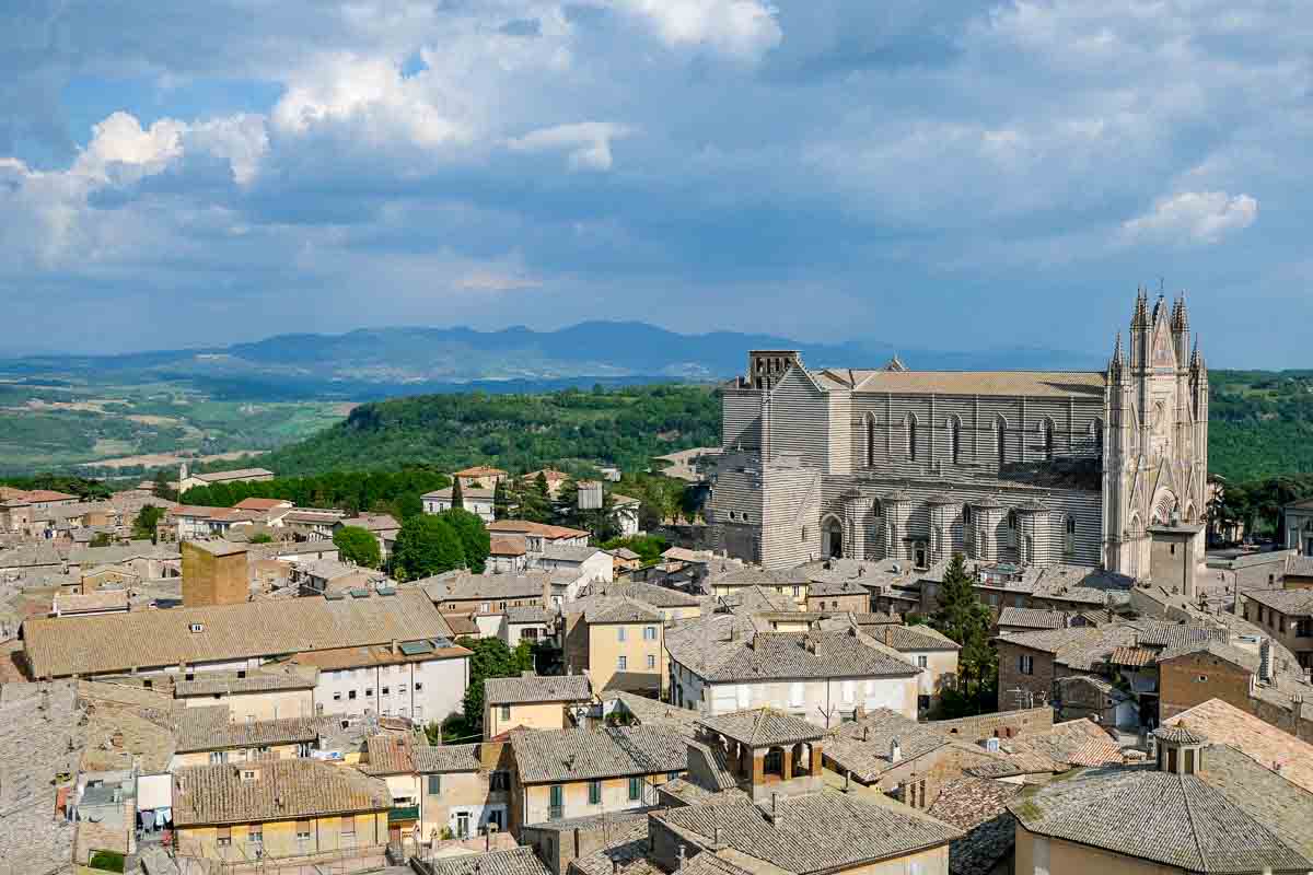 cathedral and rooftops of the city of orvieto italy with hills in background