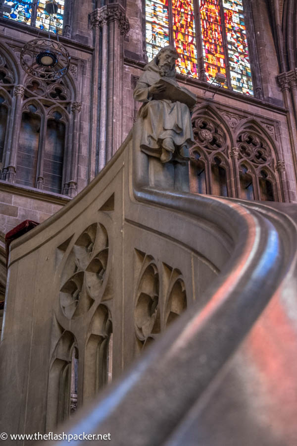 interior of church with stone sculpture of a saint reading a book on the top of a pulpit