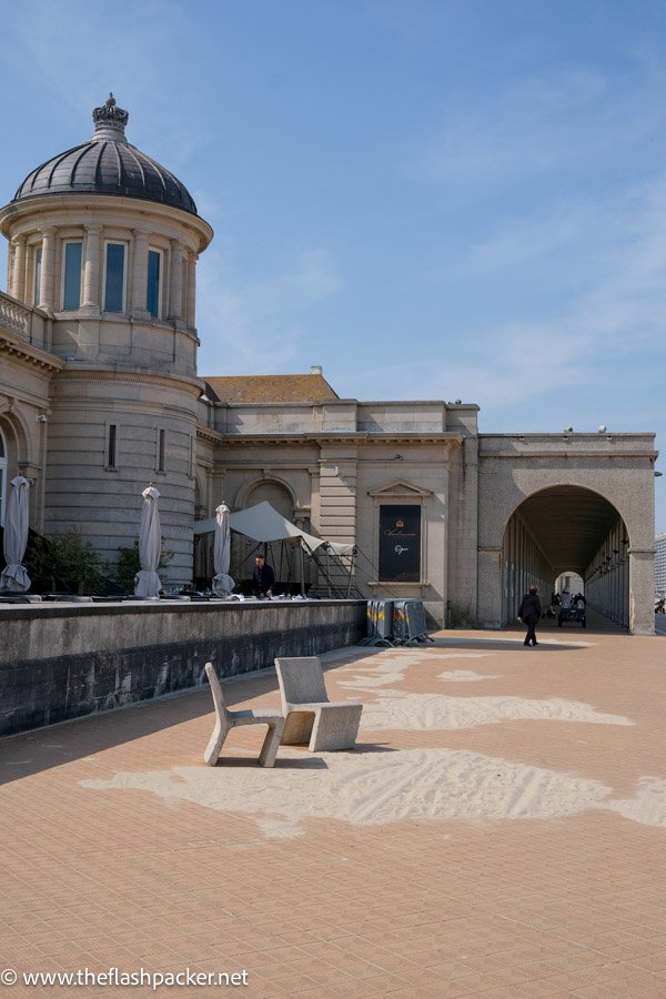 beach front promenade with stone benches and a colonnaded passageway