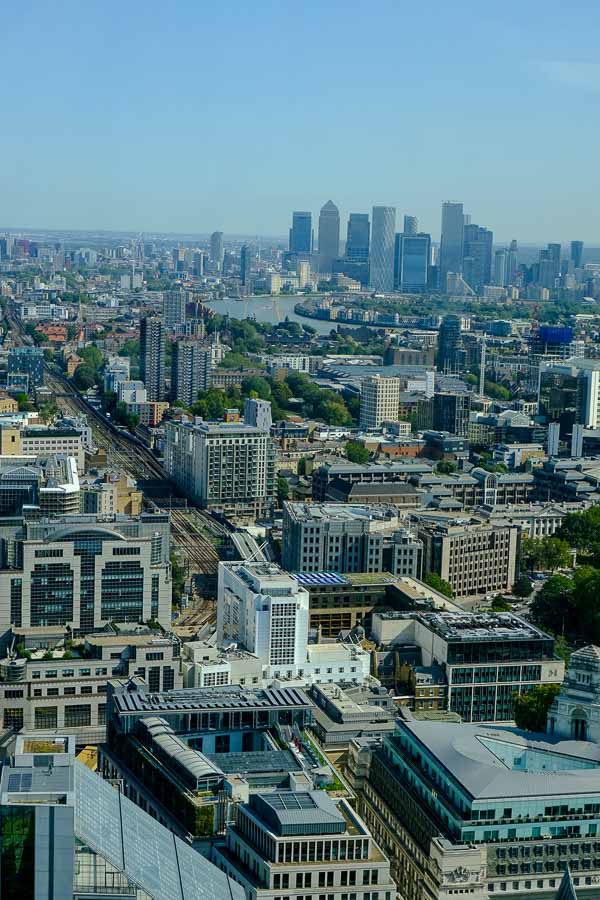 panoramic view of the rooftops of london with river and towers of canary wharf