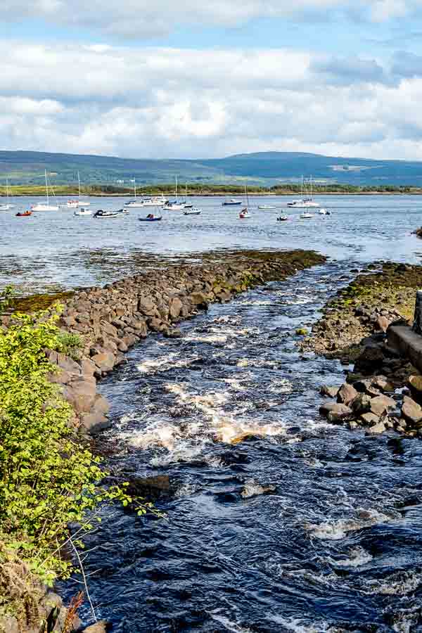 waves in harbour with hills and boats in background in tobermory mull scotland